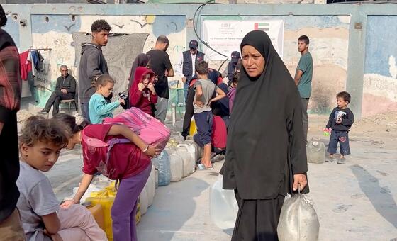 在加沙，日常生活是为满足基本需求而进行的艰难挣扎。妇女和儿童在烈日下等待数小时才能获得安全的饮用水，这是流离失所者难民营中的常见景象。